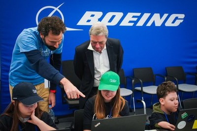A ThinkYoung instructor shows Boeing International President Sir Michael Arthur the coding school lesson as a young student works. (Boeing photo)